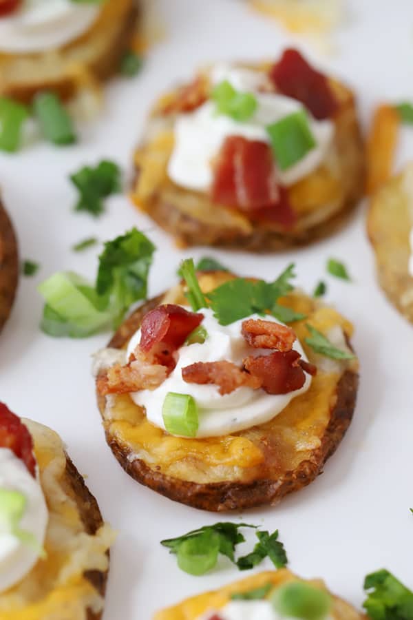 Crispy potato bites garnished with sour cream, bacon and fresh greens.