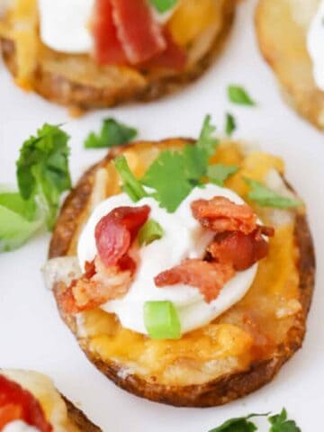 Crispy potato bites garnished with sour cream, bacon and fresh greens.