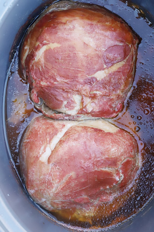 Pork roast in a slow cooker with cooking liquid.