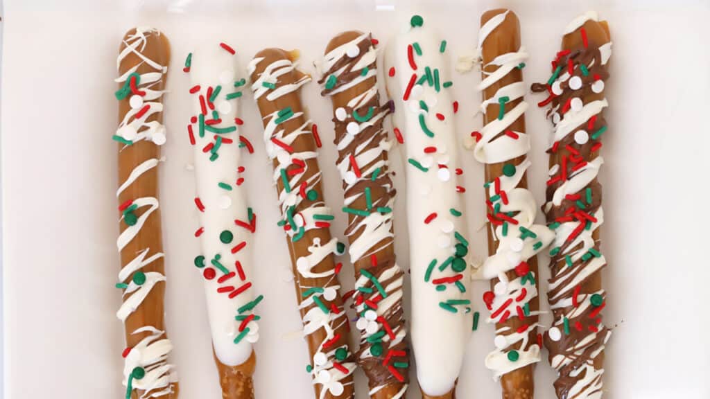 Pretzel rods dipped in chocolate and decorated with holiday sprinkles.
