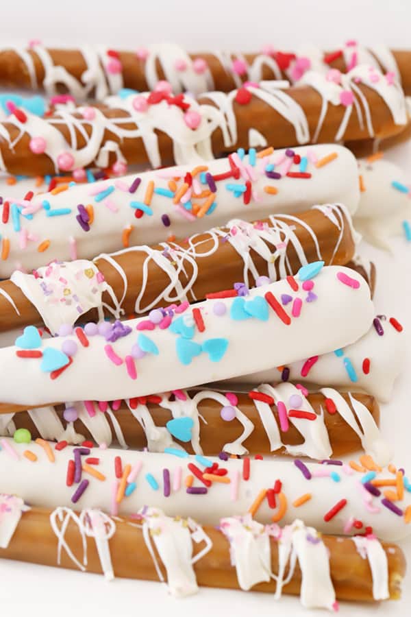 Chocolate and caramel dipped pretzel rods decorated with sprinkles.