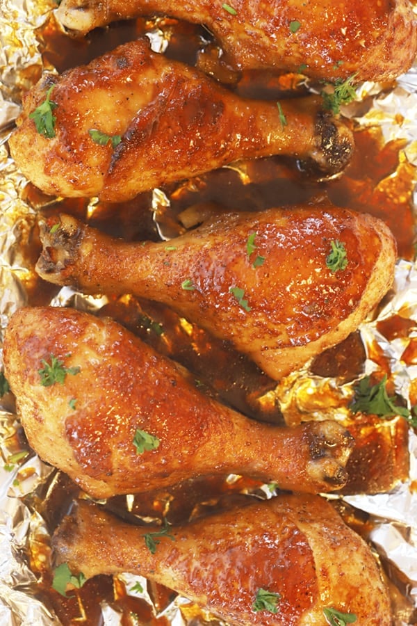 Oven-baked chicken drumsticks topped with fresh parsley.