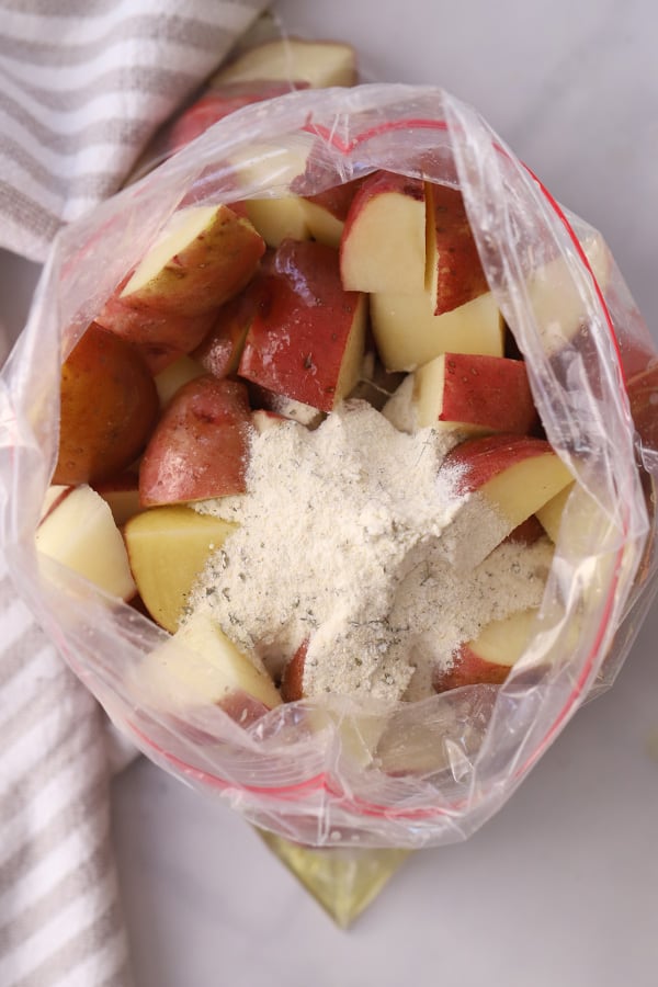 Quartered red potatoes in a ziplock bag topped with ranch seasoning mix. ingredients in a bag for recipe for ranch potatoes. roasted ranch potatoes.