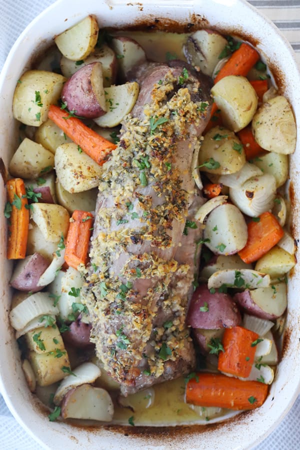 pork tenderloin roasted with with potatoes and carrots in a large baking dish.