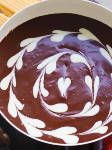 Chocolate fondue with white chocolate hearts in a fondue pot