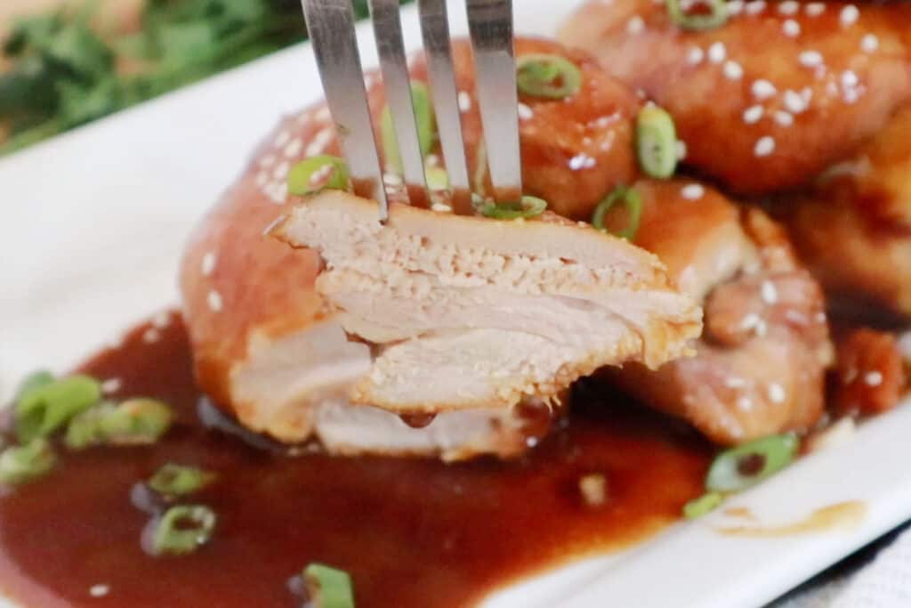 Honey Soy Chicken Thighs on a fork; honey soy chicken recipe, honey and soy sauce chicken, honey baked chicken thighs.