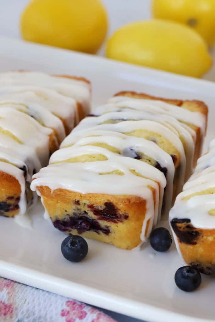 Lemon Blueberry Bread recipe  on a white platter with fresh blueberries