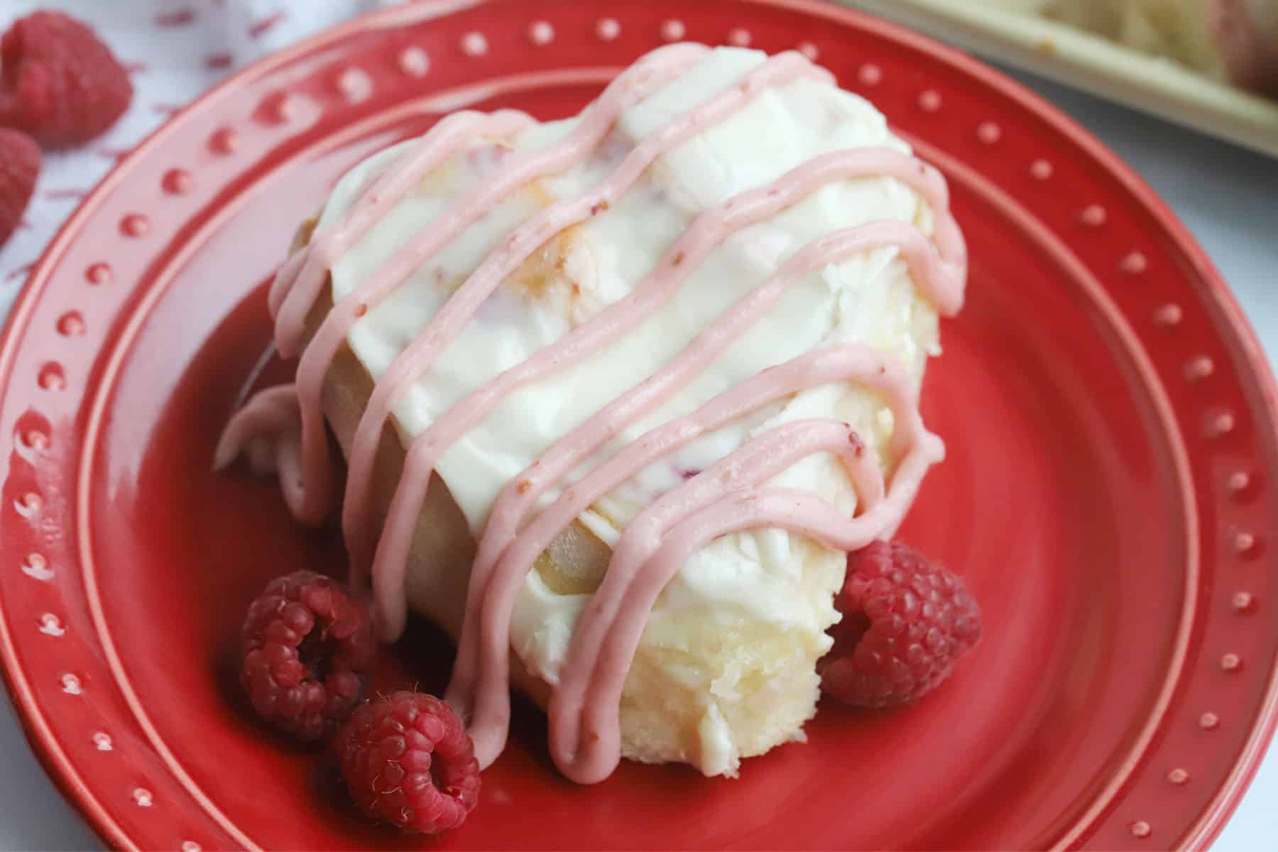raspberry sweet roll with lemon cream cheese Frosting, cinnamon raspberry rolls decorated for valentine's day.