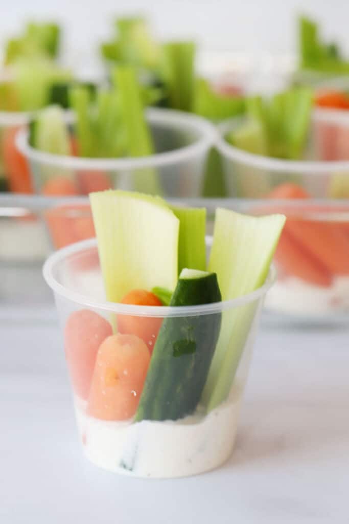 Vegetables in a small plastic cup with simple ranch dressing recipe at the bottom for dipping.