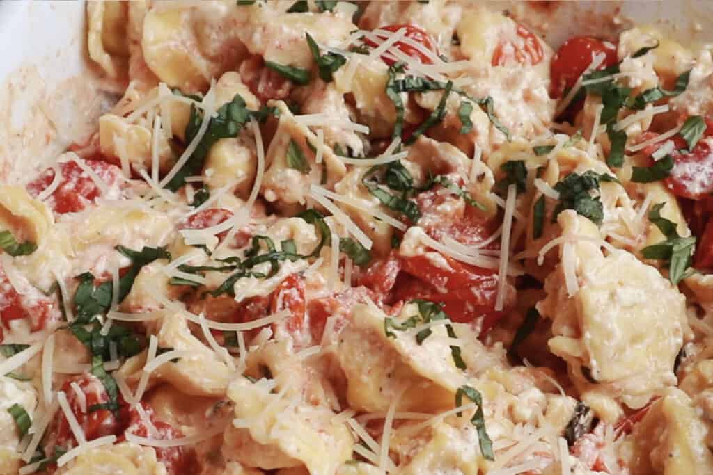 tikok feta tomato pasta recipe mixed in a white baking dish