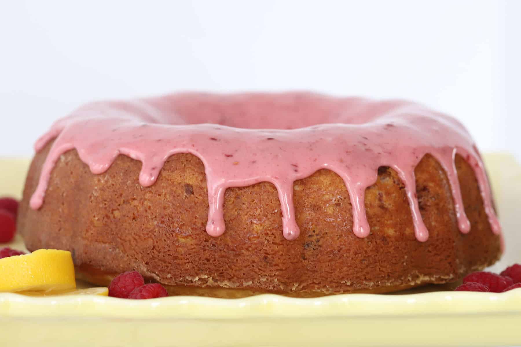 A full bundt cake topped with raspberry glaze for bundt cake, drizzling down the sides.