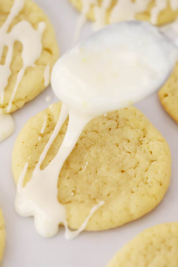 Frosting a lemon cookie with glaze, using an easy lemon glaze recipe.