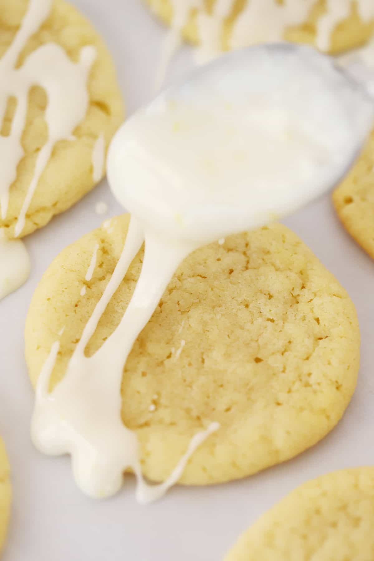 A lemon cookie being drizzled with glaze.