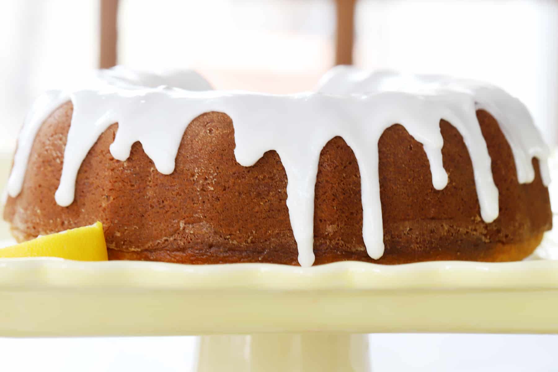 The side view of a full glazed bundt cake on a cake stand.