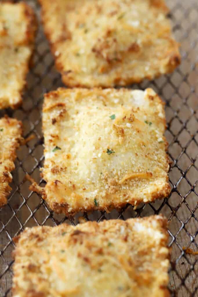 Toasted ravioli in an air fryer basket.