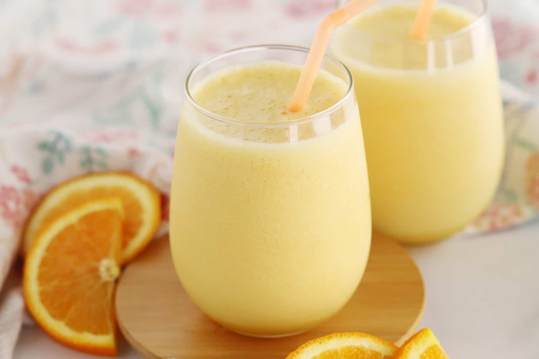 A table with an Orange Julius poured into a glass with a straw.