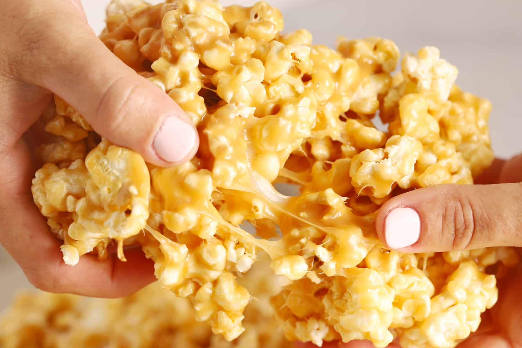 Two hands holding and pulling apart fresh caramel corn.