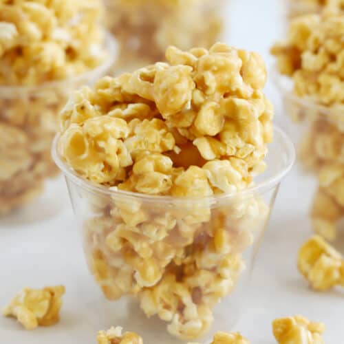 Caramel popcorn inside plastic cups on a table.
