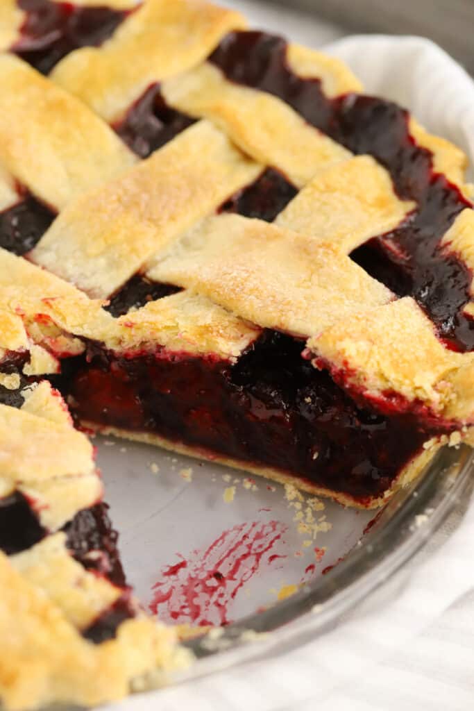 A lattice-top pie in a pie dish with a slice removed.