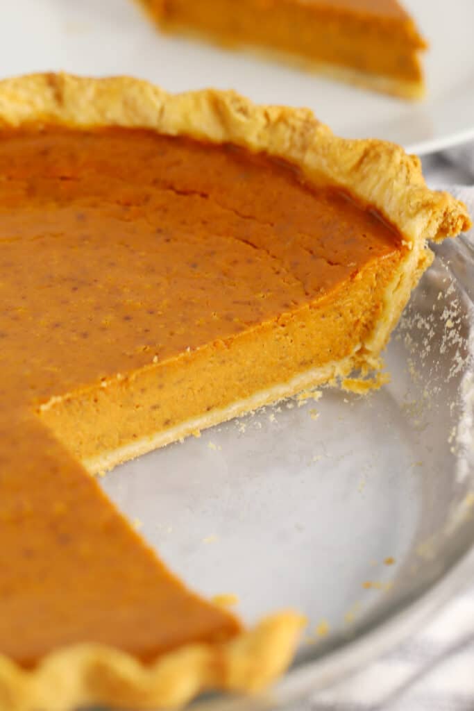 Pumpkin pie baked in a pie plate with a slice removed.