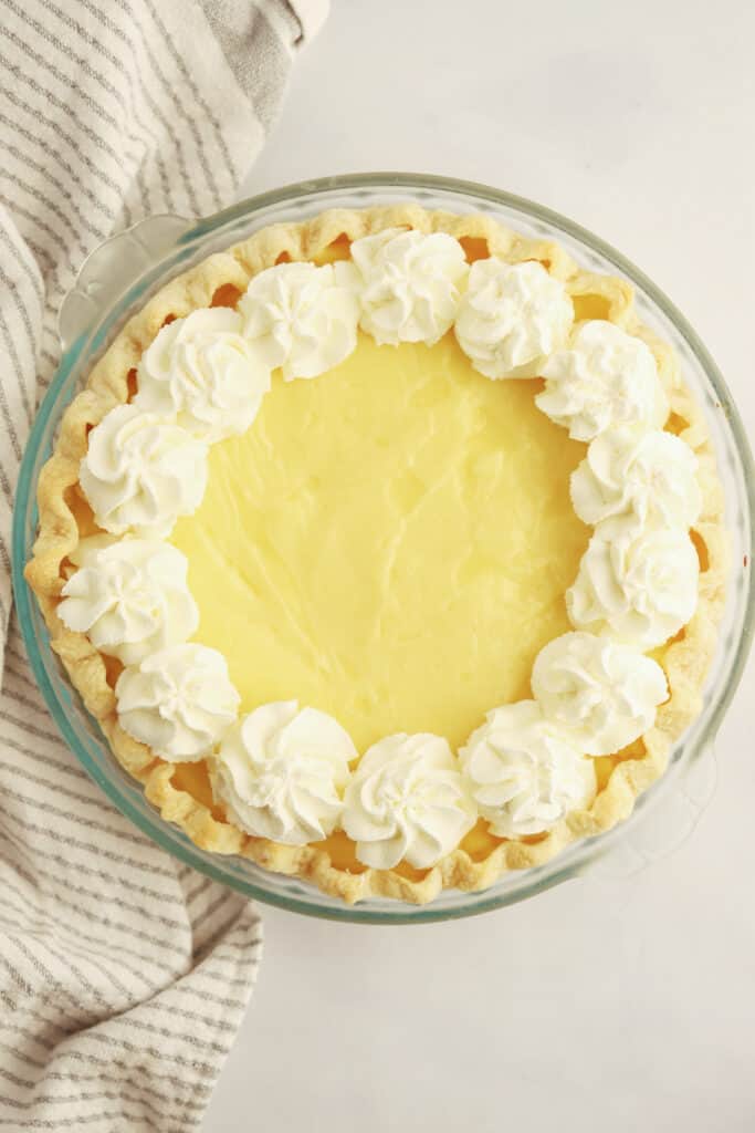 A pie in a glass pie dish from above topped with piped whipped cream.