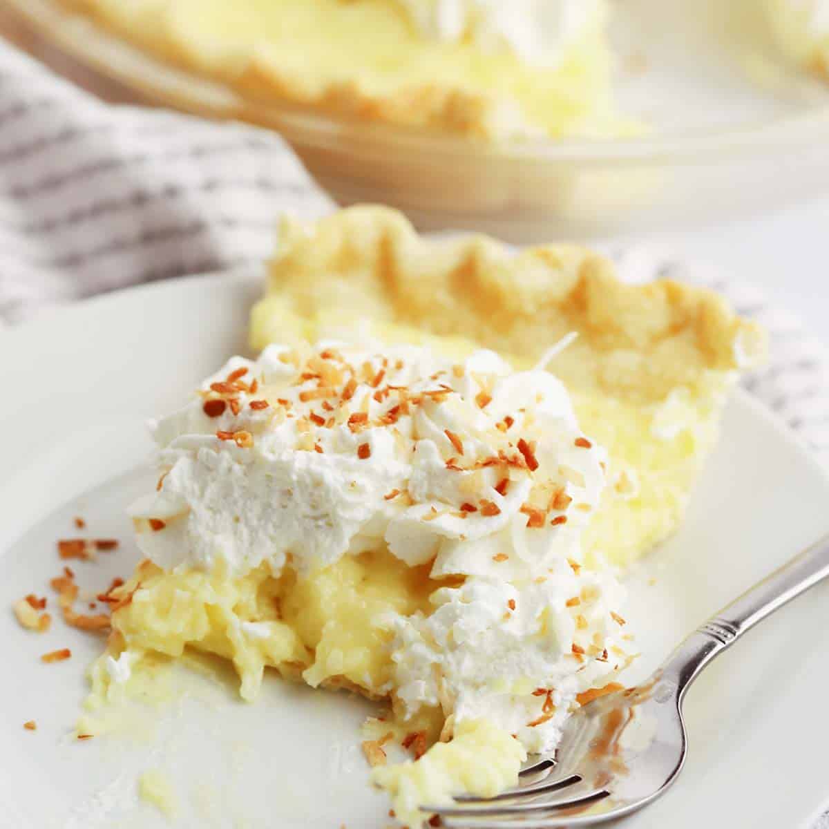 a slice of coconut cream pie on a white plate