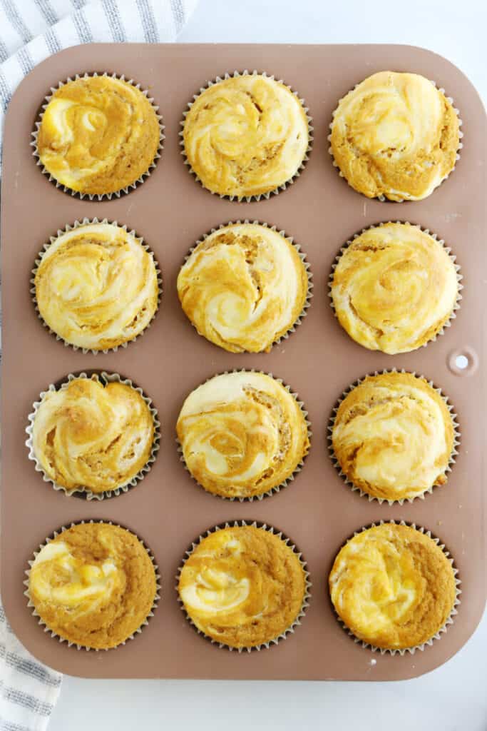 Baked pumpkin cheesecake muffins in a muffin pan.