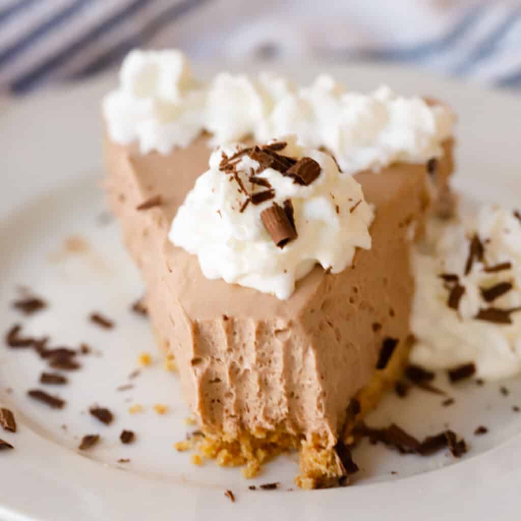 A slice of chocolate cheesecake topped with whipped cream and chocolate shavings.