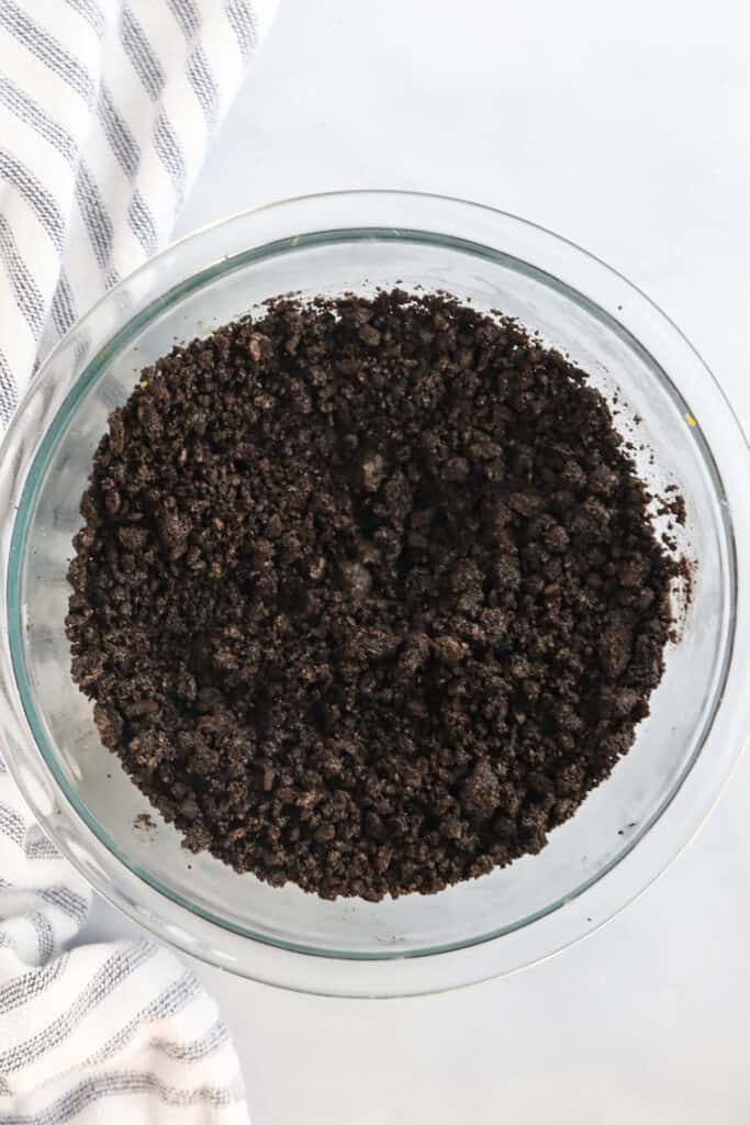 A glass mixing bowl full of Oreo cookie crumbs.