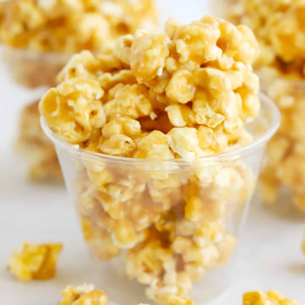 Caramel popcorn inside plastic cups on a table.