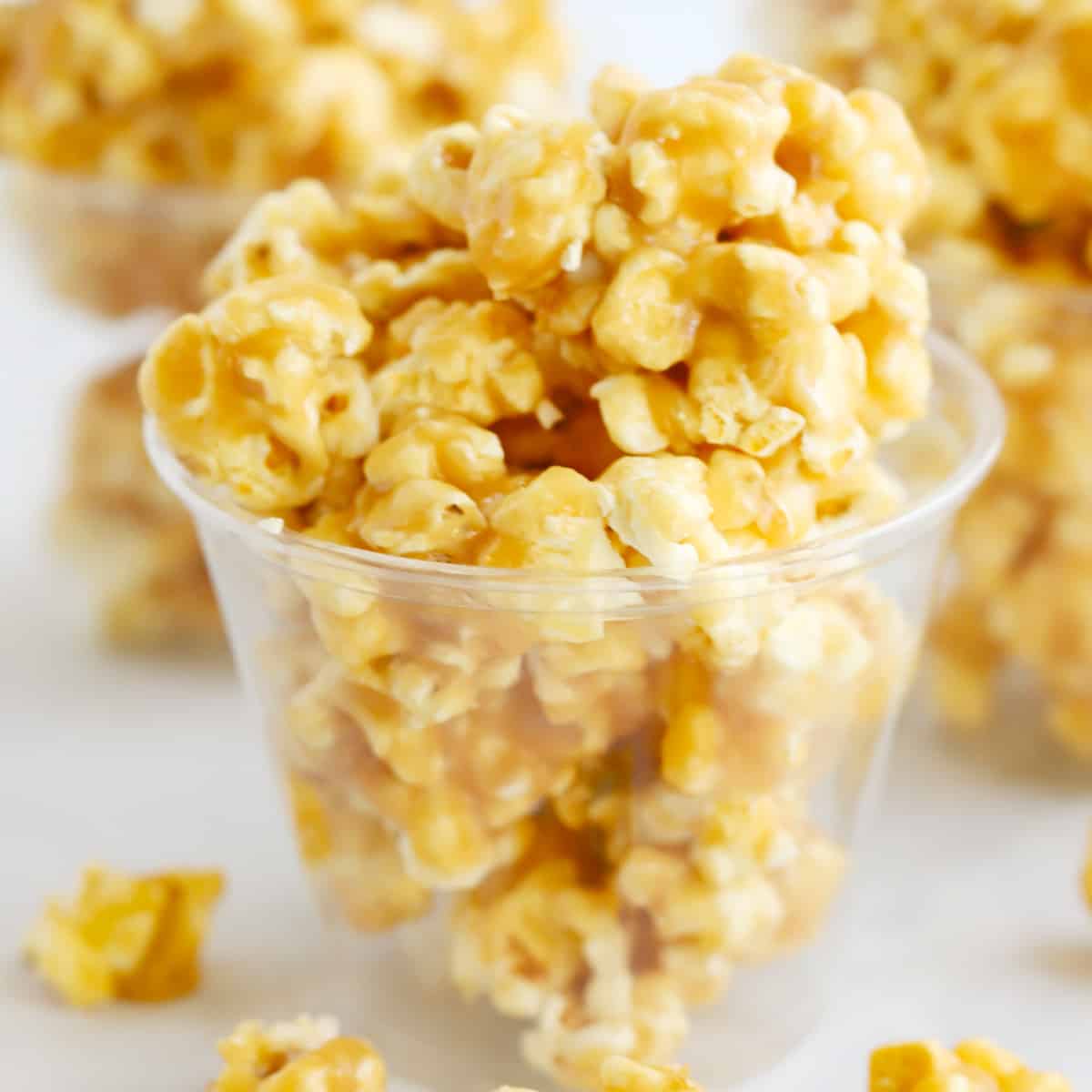Caramel popcorn inside plastic cups on a table. how to make caramel popcorn. Easy caramel popcorn recipe.