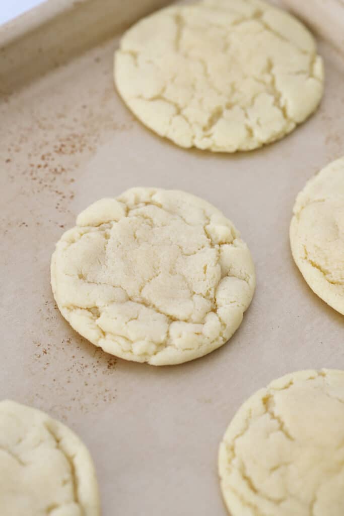 Baked soft chewy sugar cookies on a baking sheet, sugar cookies chewy cooling.