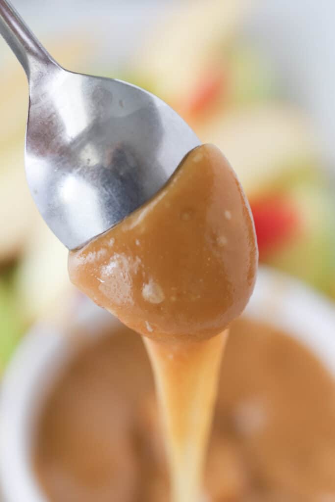 A spoon dripping with caramel sauce.
