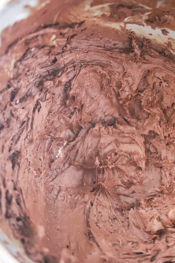 A close up picture of easy buttercream chocolate frosting in a large bowl, fluffy chocolate frosting. chocolate glaze for bundt cake. Best chocolate buttercream frosting.