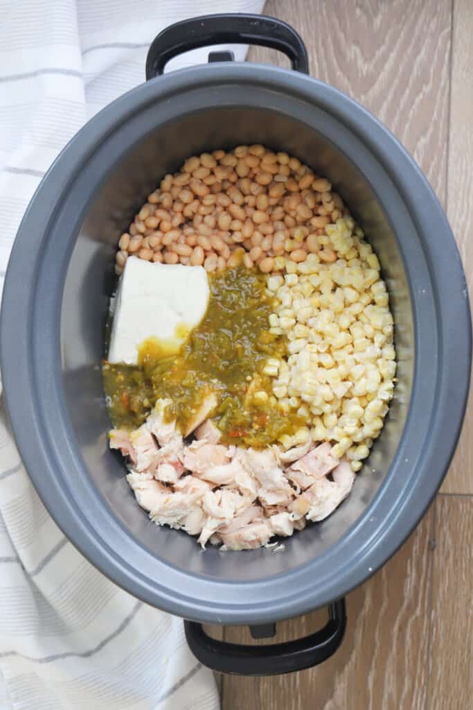 A crockpot full of chicken, beans, corn, enchilada sauce and cream cheese.