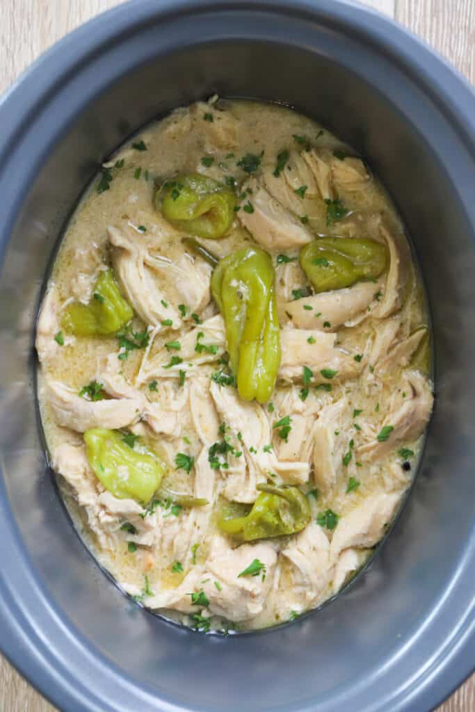 A slow cooker filled with shredded chicken and pepperoncini. Mississippi pot roast chicken. Mississippi chicken in crock pot. Mississippi chicken recipe. shredded bbq chicken crock pot. Mississippi chicken instant pot.