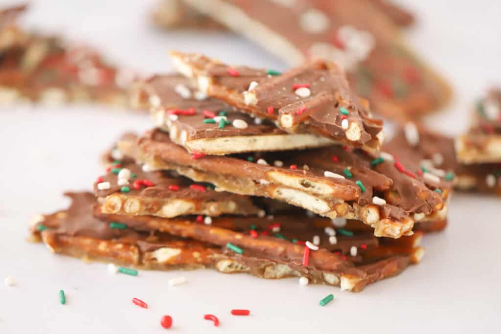 Pieces of pretzel toffee stacked on each other and topped with red, white and green sprinkles. pretzel candy recipes. Christmas crack with pretzels.