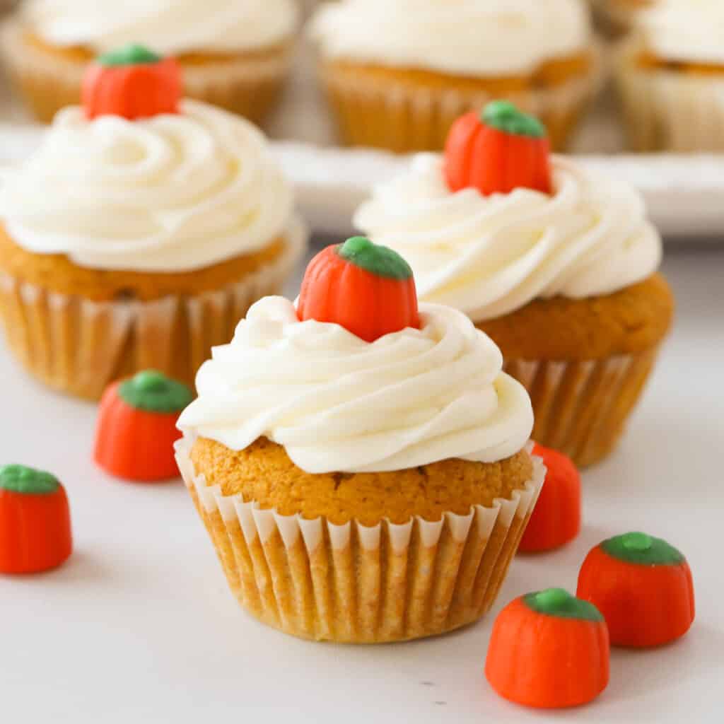 Pumpkin cupcakes topped with frosting and pumpkin candies.