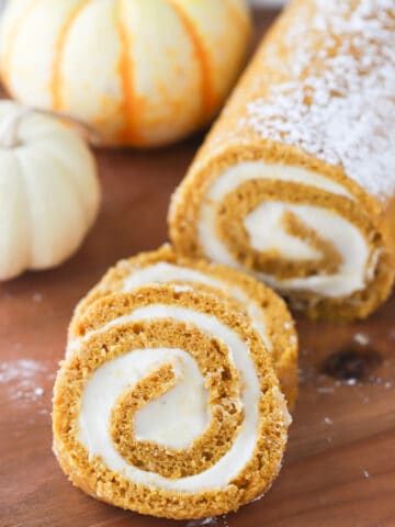 Pumpkin roll with cream cheese frosting on wood cutting board