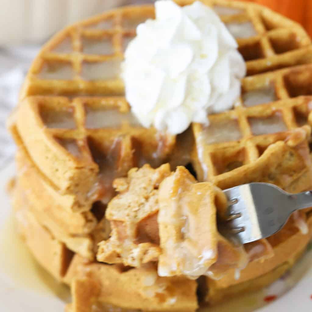 homemade pumpkin waffles being eaten with a fork.