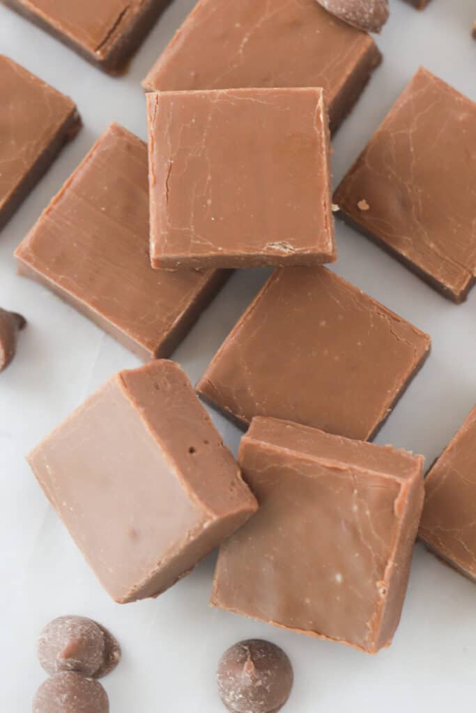how to make this homemade chocolate fudge recipe (easy). Squares of homemade fudge cut and resting on a tray.