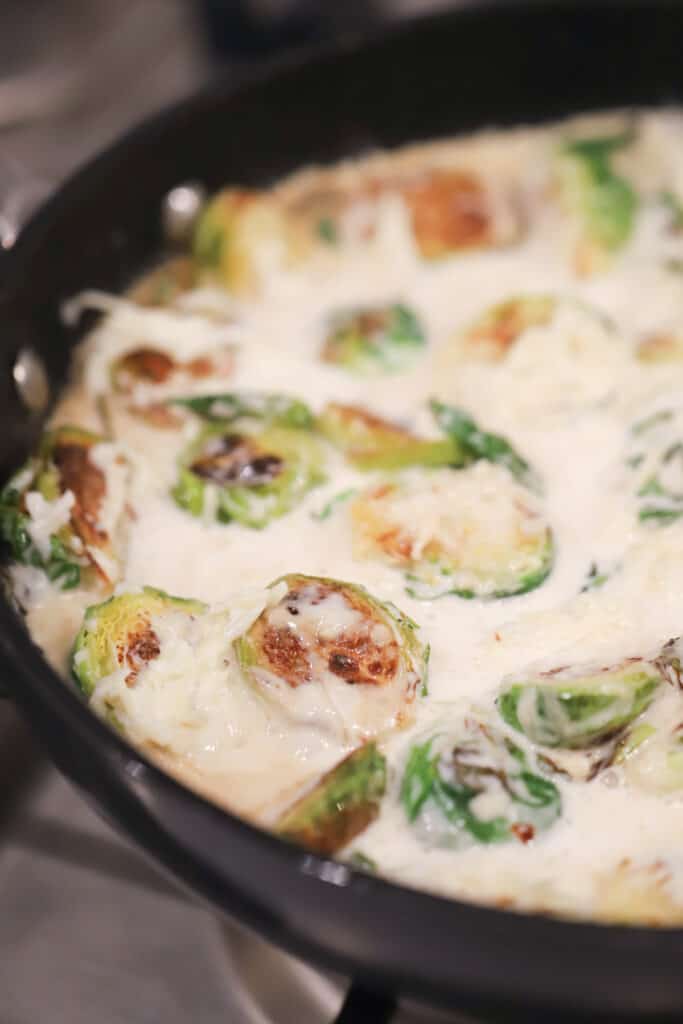 A saute pan with Brussels sprouts in a cream sauce.