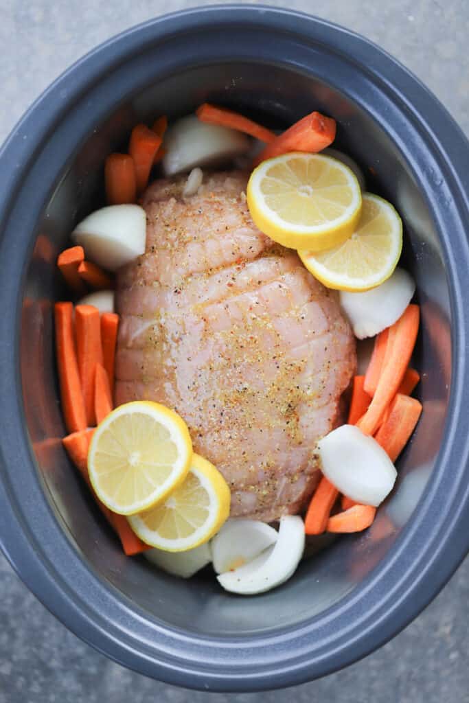 turkey breast in a crockpot with carrots, onions, and marinade.