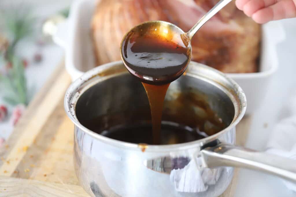 how to make a honey glaze for ham, A ladle spooning ham glaze in a sauce pot, simple honey glaze for ham, honey gam glaze. 
