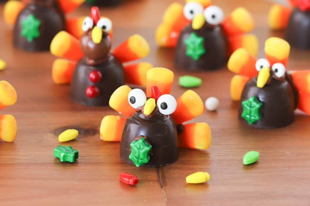 Chocolate turkeys made with candy corns, chocolate candies and other decorations on a table.