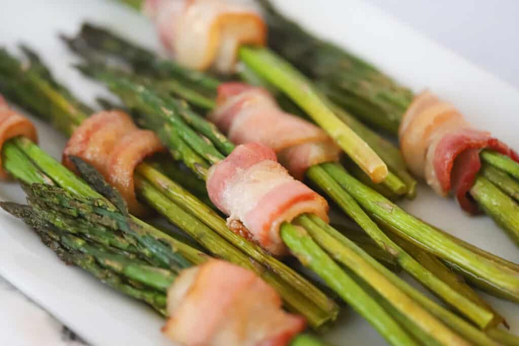 Bundles of bacon wrapped asparagus in air fryer, in the air fryer baskey