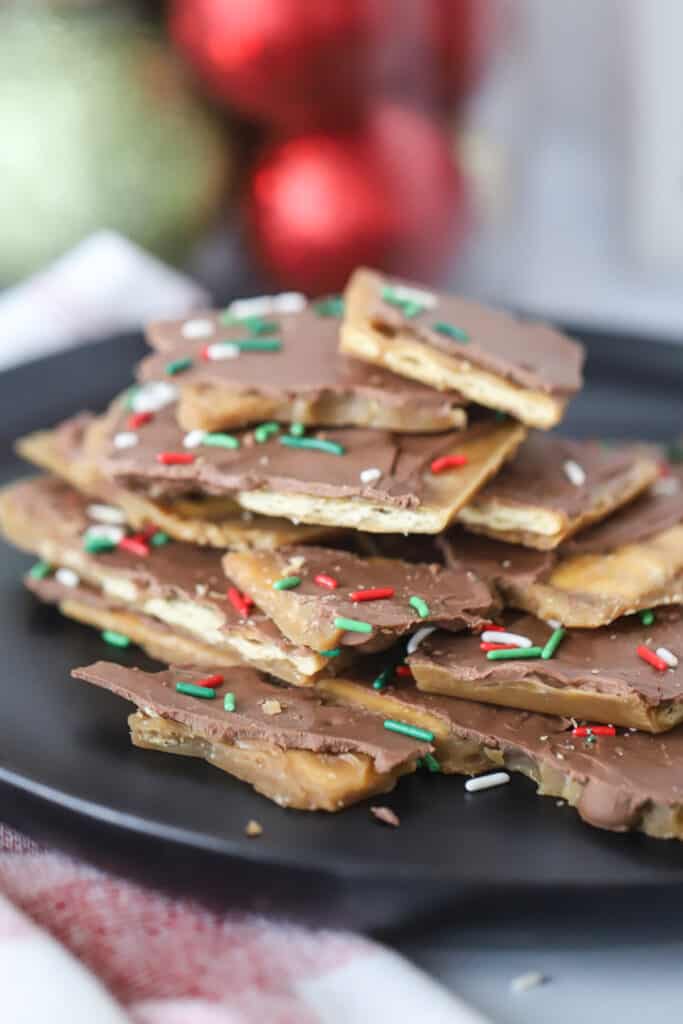 saltine cracker toffee with christmas sprinkles on a black plate