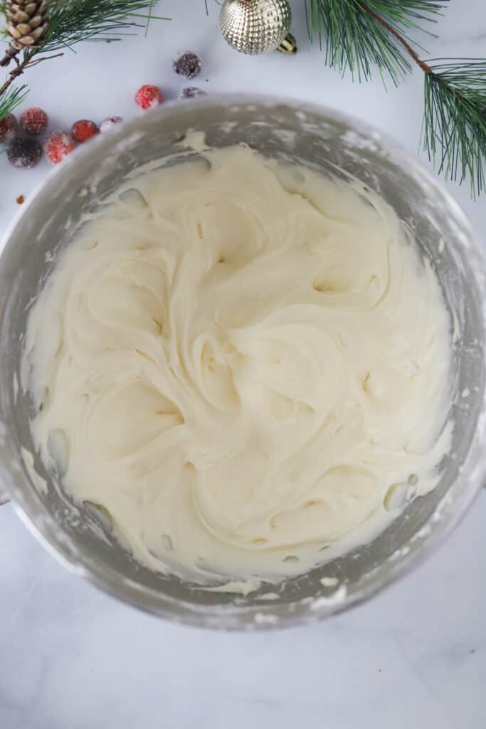 Cream Cheese frosting in a large stainless steel mixing bowl, ready to use for our best homemade cinnamon rolls recipe.