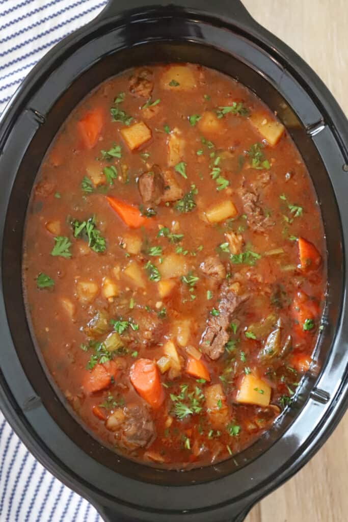 Beef stew recipes in a crock pot on a table, browned beef stew recipe. 
