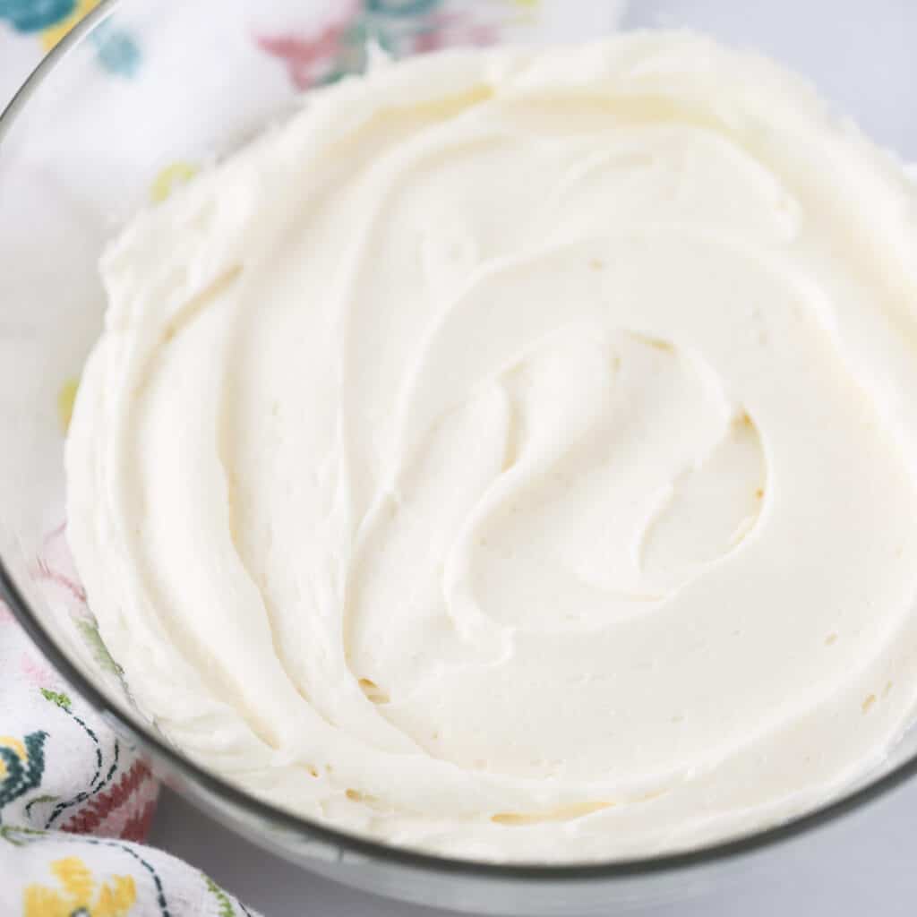 Cream cheese frosting for cinnamon rolls, whipped cream cheese frosting in a glass mixing bowl.